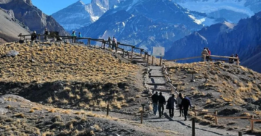 Besucher auf dem Kiesweg und dem Holzsteg zum Aussichtspunkt an der Lagune von Horcones, dahinter der Berg